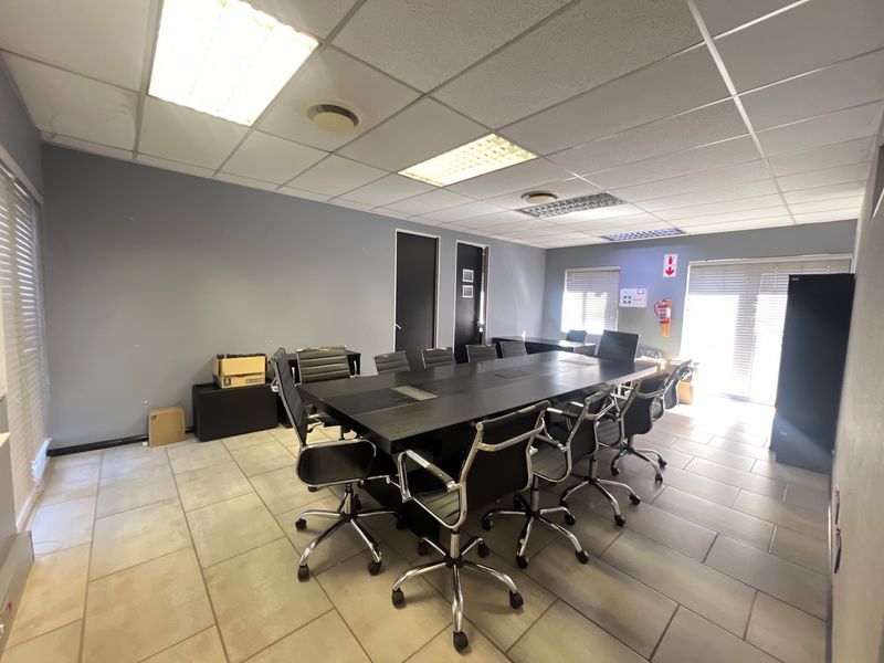A functional commercial office space featuring tiled flooring, suspended ceilings with recessed lighting, and large windows with venetian blinds.