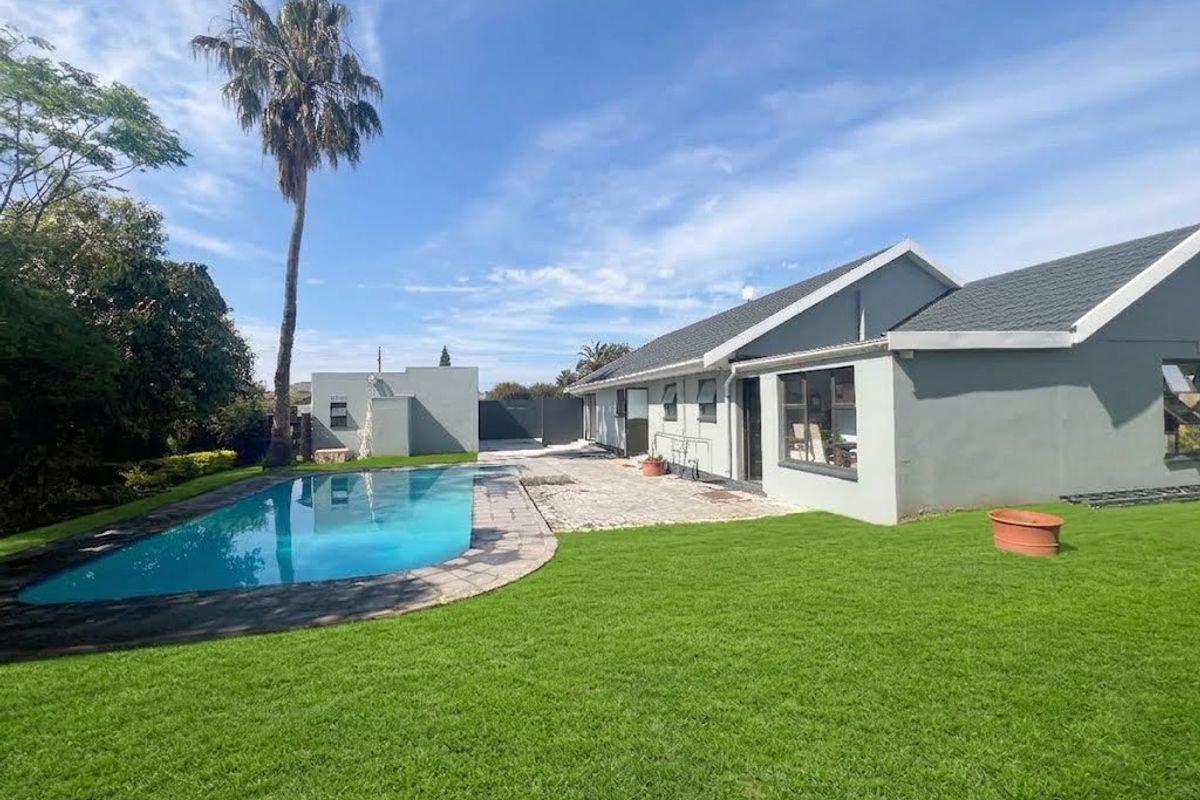 Rear exterior view featuring a swimming pool, paved patio area, and a well-maintained lawn set against the house structure.