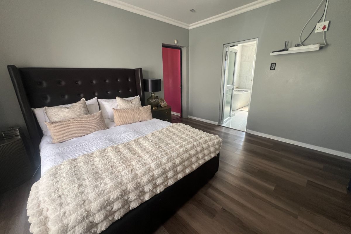 Spacious bedroom featuring laminate flooring, coving, and direct access to an en-suite bathroom.