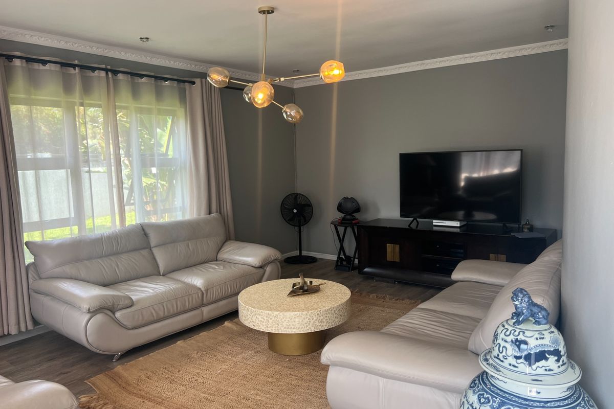 A well-maintained living room featuring crown molding, recessed lighting, and durable laminate flooring, providing a comfortable and inviting space.