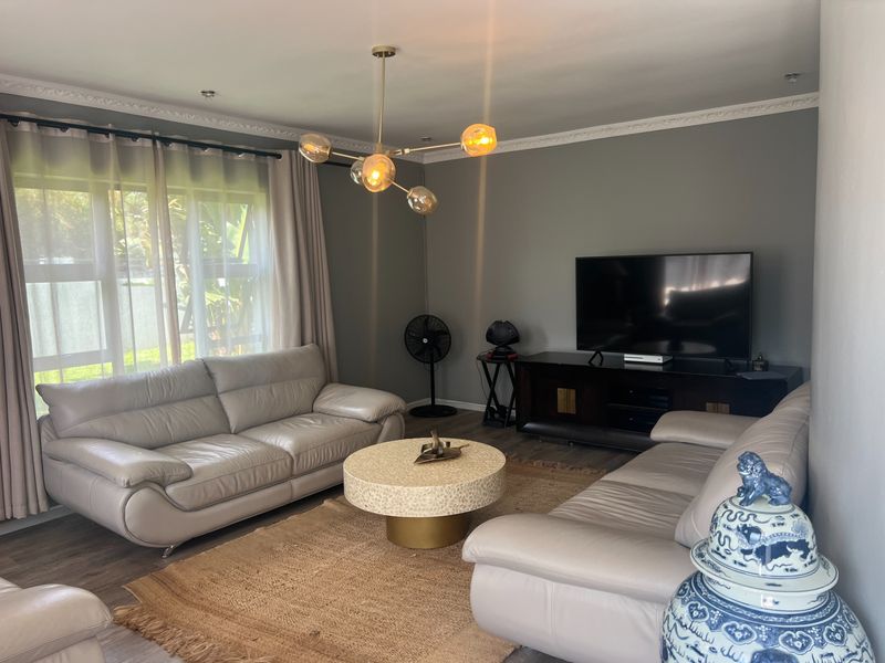 A well-maintained living room featuring crown molding, recessed lighting, and durable laminate flooring, providing a comfortable and inviting space.