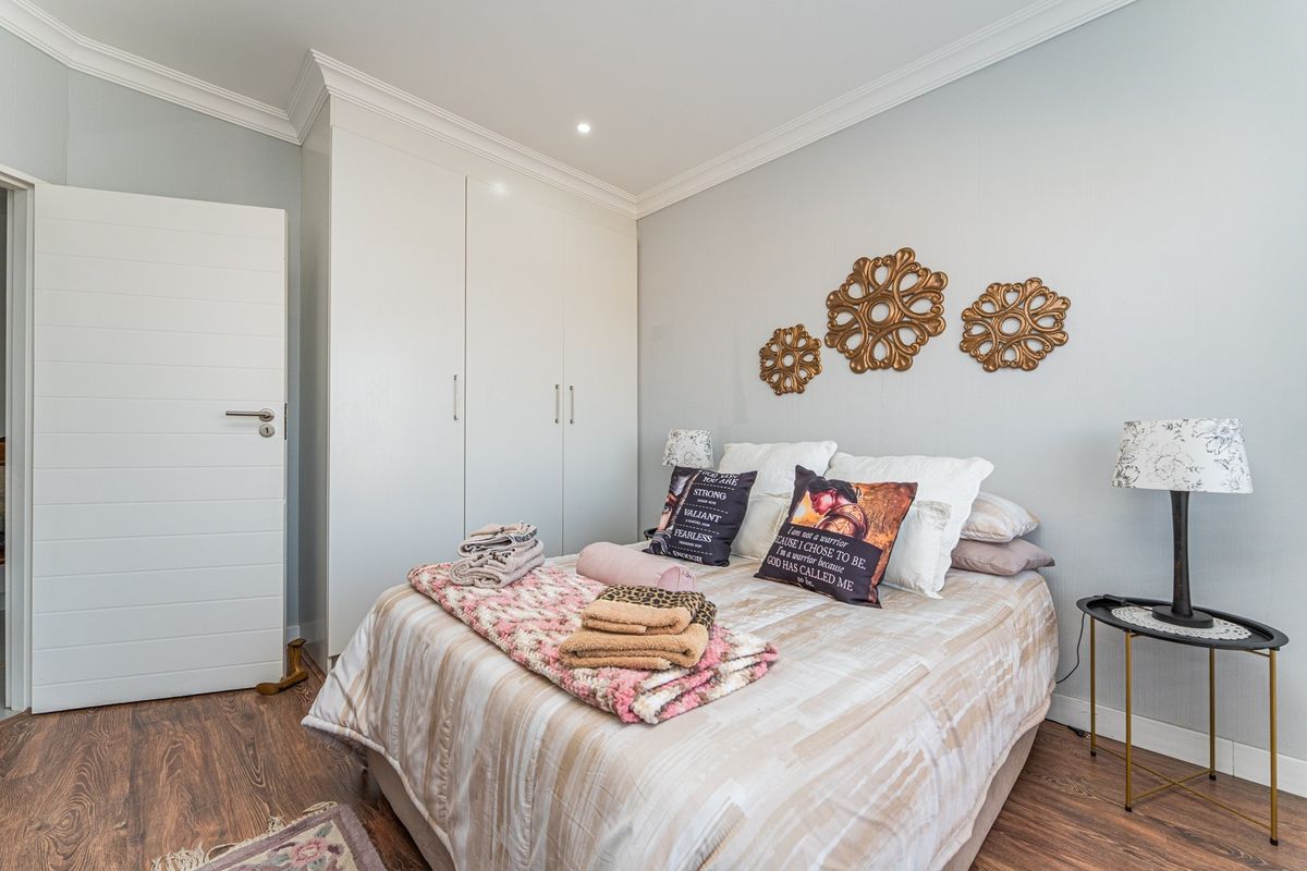 A well-maintained bedroom featuring laminate flooring, built-in cupboards, and elegant ceiling cornicing, providing a clean and functional living space.