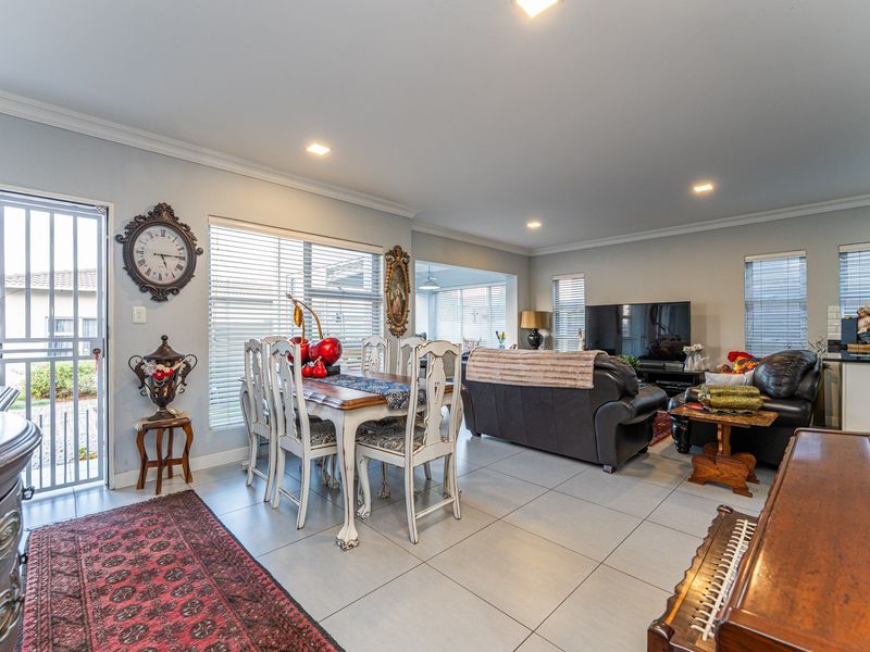 Spacious open-plan living and dining area featuring neutral tiled flooring, recessed lighting, and direct access to the exterior through a secure gate.