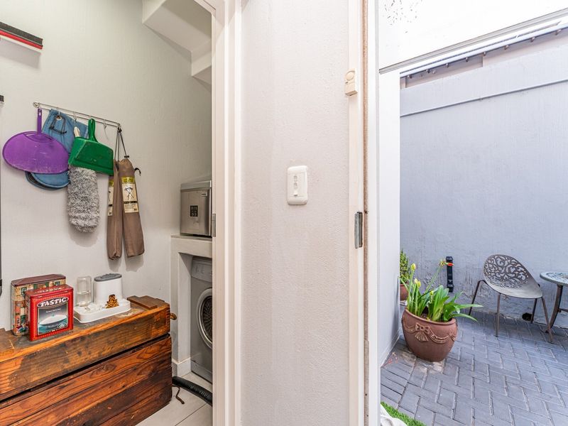 A compact laundry alcove featuring built-in appliance space, leading directly out to a private paved courtyard area.
