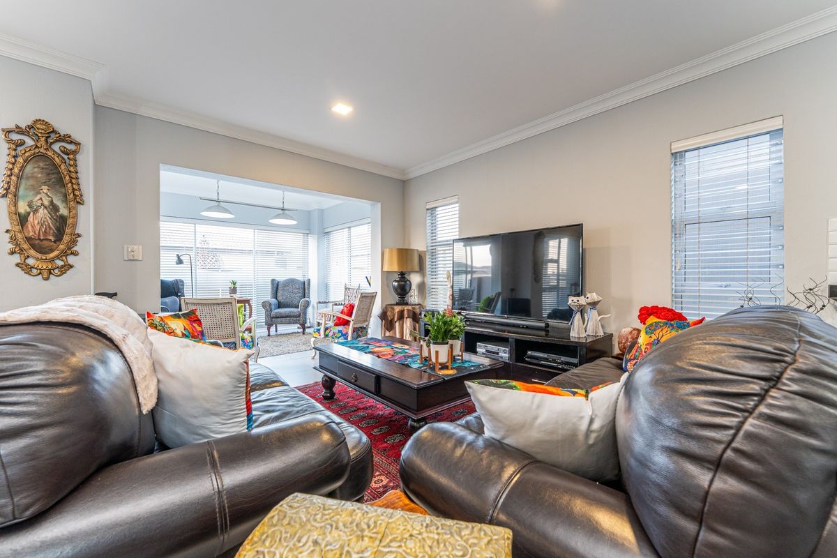 A comfortable living room featuring crown molding, recessed lighting, and large windows with venetian blinds, creating a bright and inviting space.