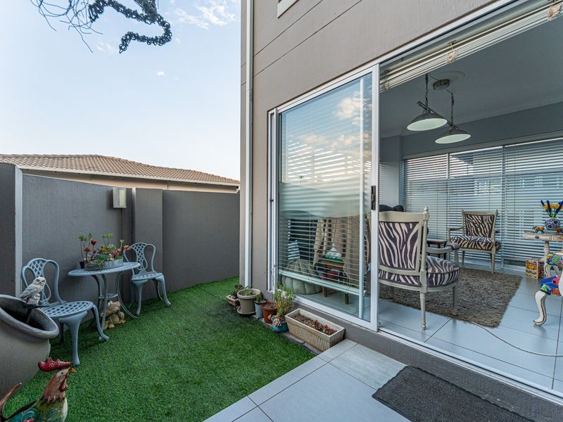A private outdoor patio area featuring artificial turf, tiled flooring, and a large sliding glass door providing seamless access to the interior living space.