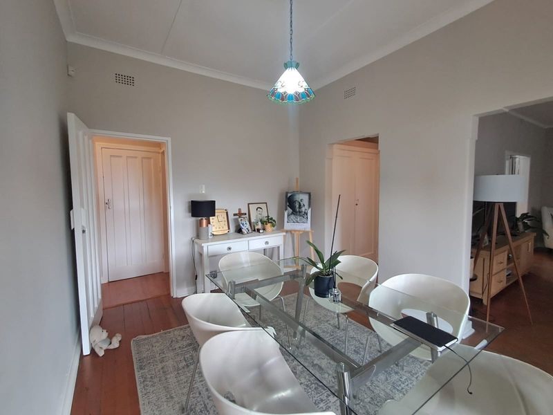 A dining room featuring original timber flooring, coved cornicing, and a decorative pendant light fixture, providing a neutral canvas for interior updates.