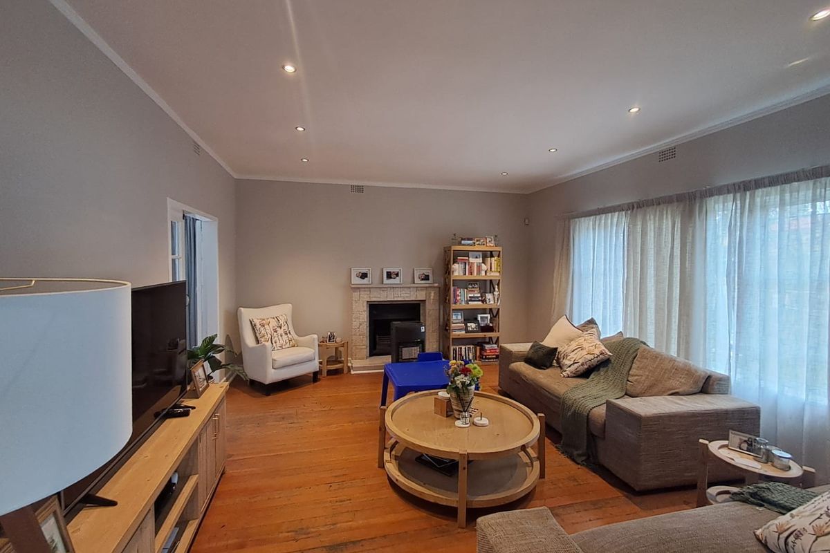 A spacious living room featuring warm timber flooring, a central fireplace, and recessed downlighting, creating a comfortable and inviting atmosphere.