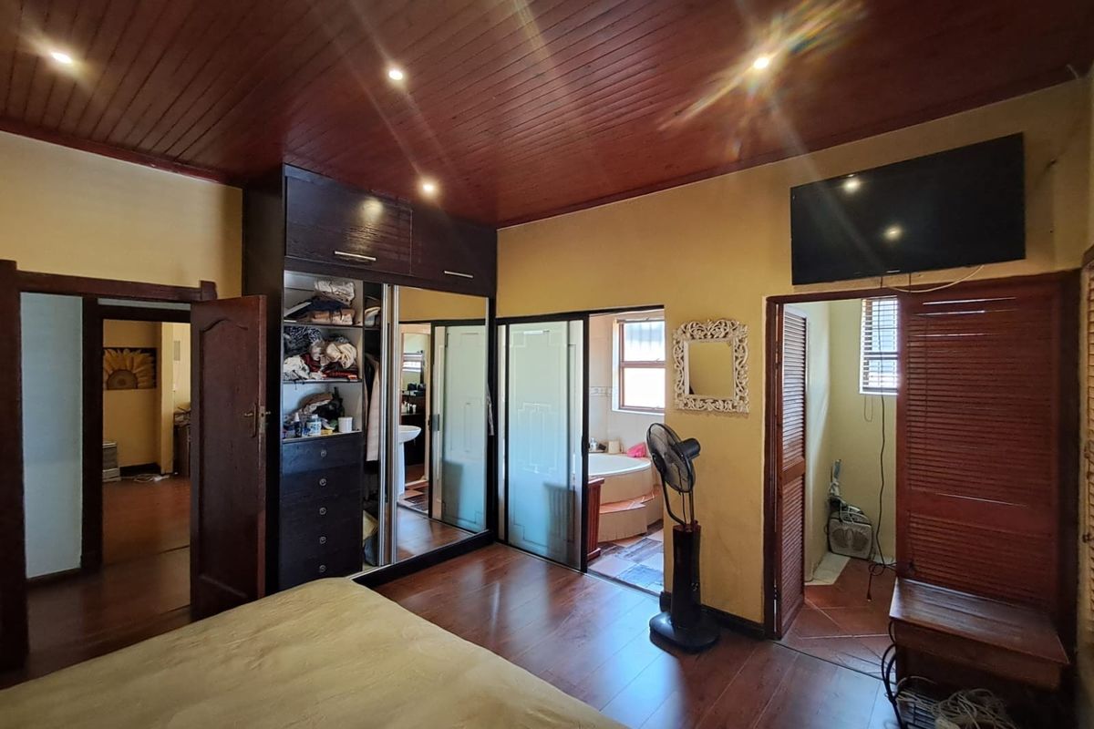 Spacious bedroom featuring timber ceilings, recessed lighting, built-in mirrored cupboards, and direct access to an en-suite bathroom.