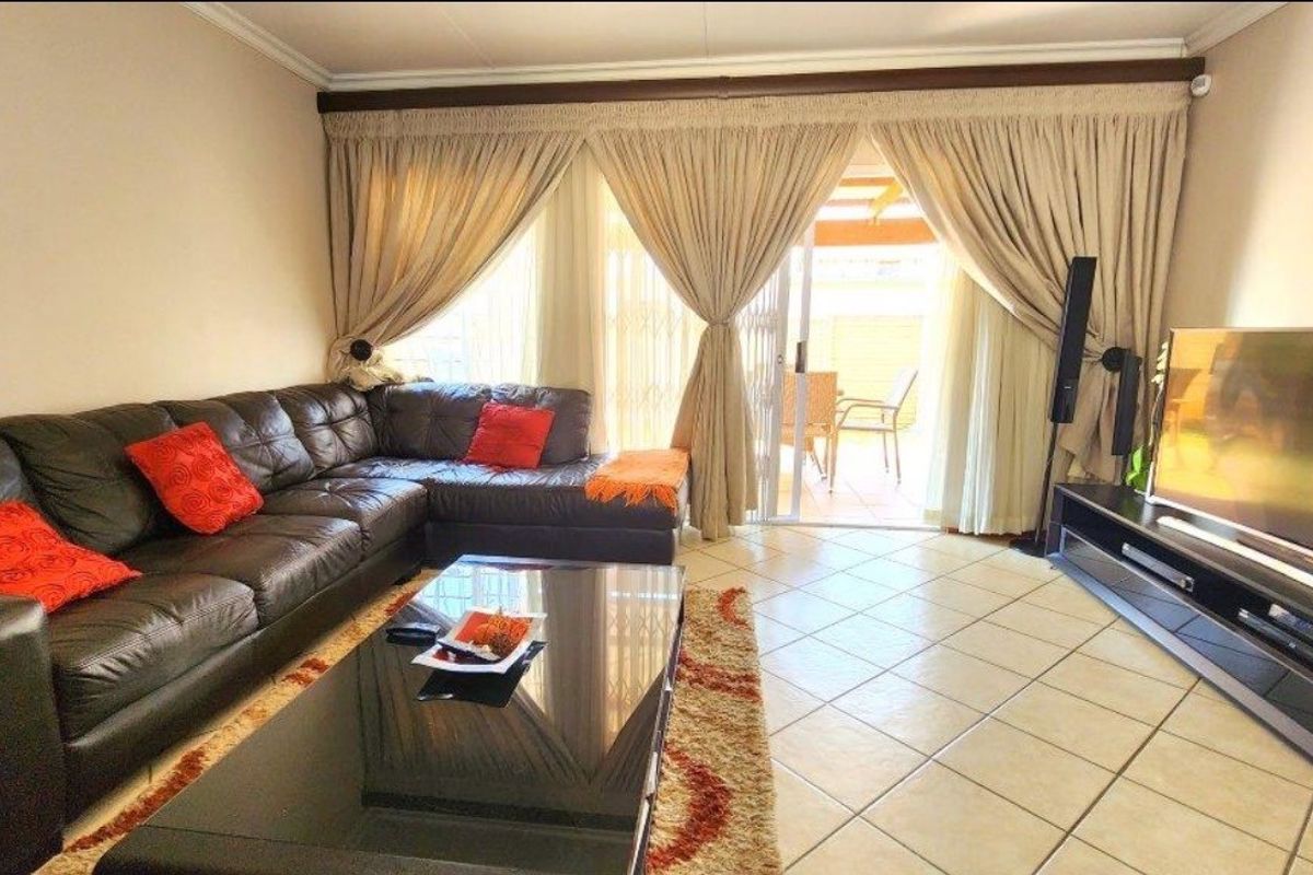 A comfortable living room featuring tiled flooring and a sliding glass door that provides direct access to the outdoor patio area.