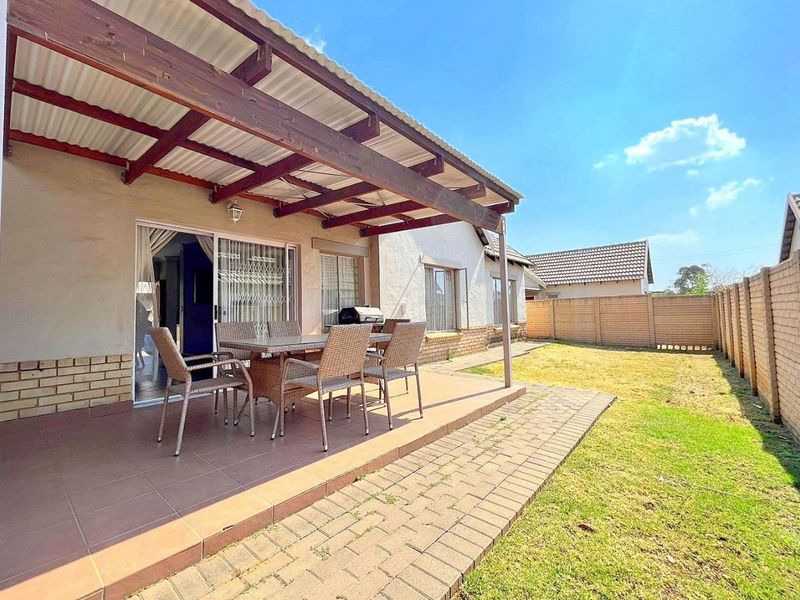 A covered patio area featuring a timber pergola and tiled flooring, providing direct access to the rear garden and paved walkway.