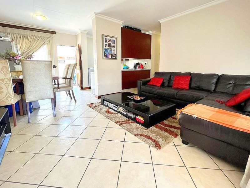 Open-plan living and dining area featuring tiled flooring, neutral walls, and built-in cabinetry, providing a functional and connected layout for daily living.