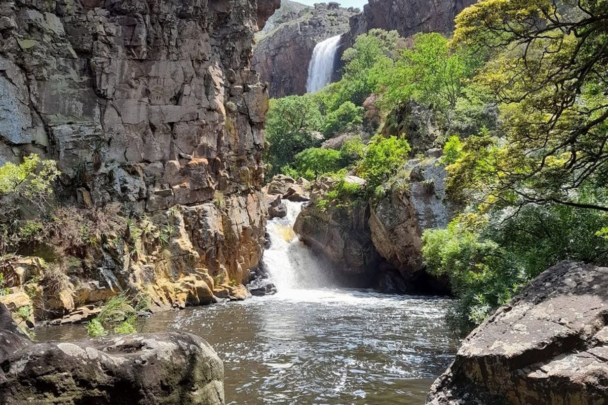 A scenic view of a natural waterfall cascading into a rocky gorge and pool, showcasing the property's surrounding landscape.