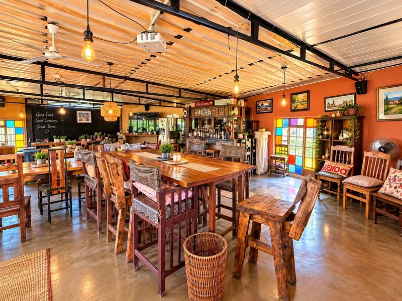 Spacious entertainment area featuring a built-in bar, exposed steel roof structure, polished concrete floors, and decorative stained glass accents.