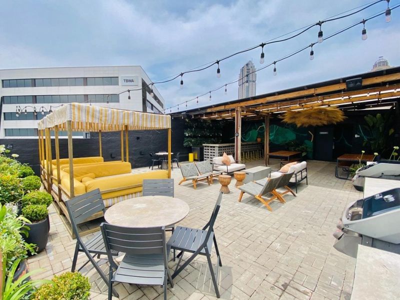 Spacious rooftop patio featuring a timber pergola, string lighting, and a built-in bar area, perfect for outdoor entertaining.