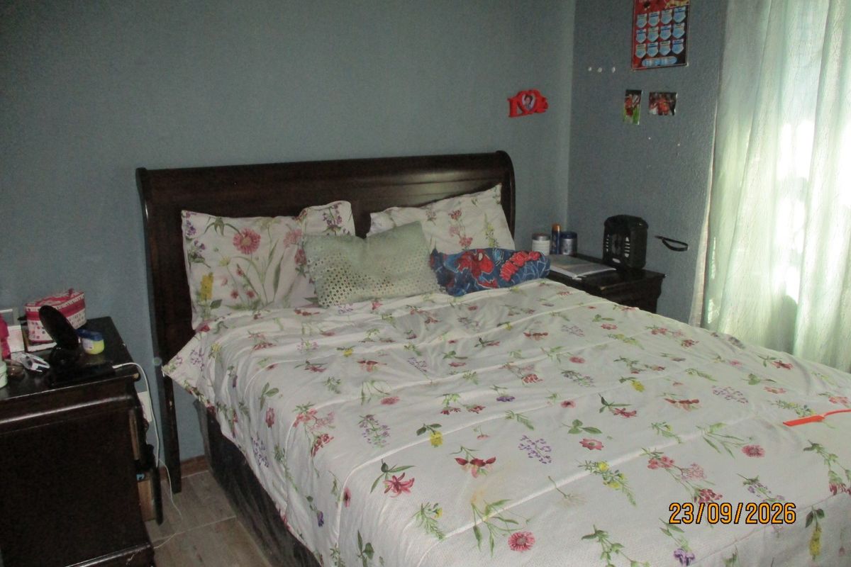 A standard bedroom featuring tiled flooring and window treatments, providing a functional living space.