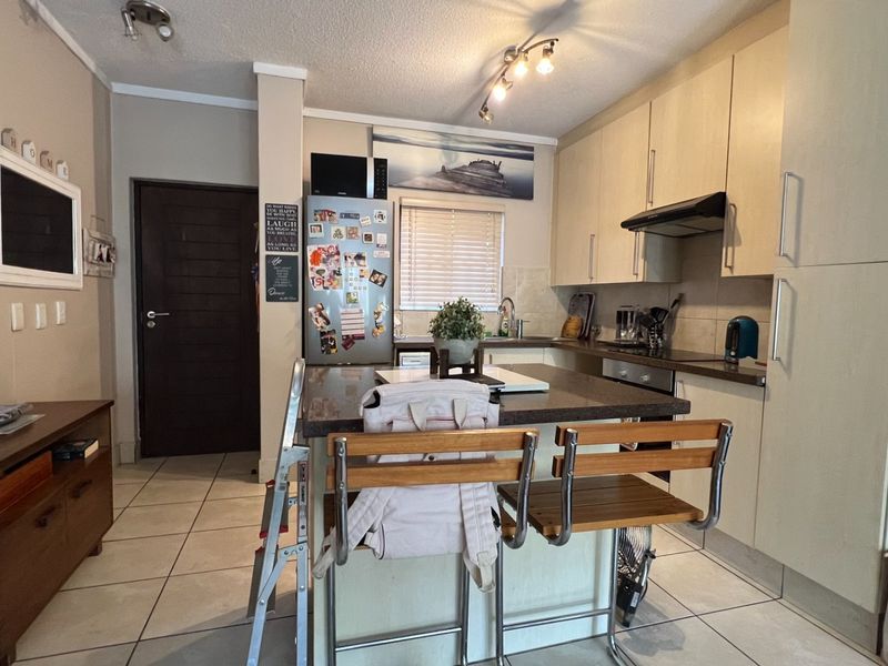 A functional kitchen featuring light-toned cabinetry, stone countertops, a central island, and tiled flooring, providing a practical layout for daily use.