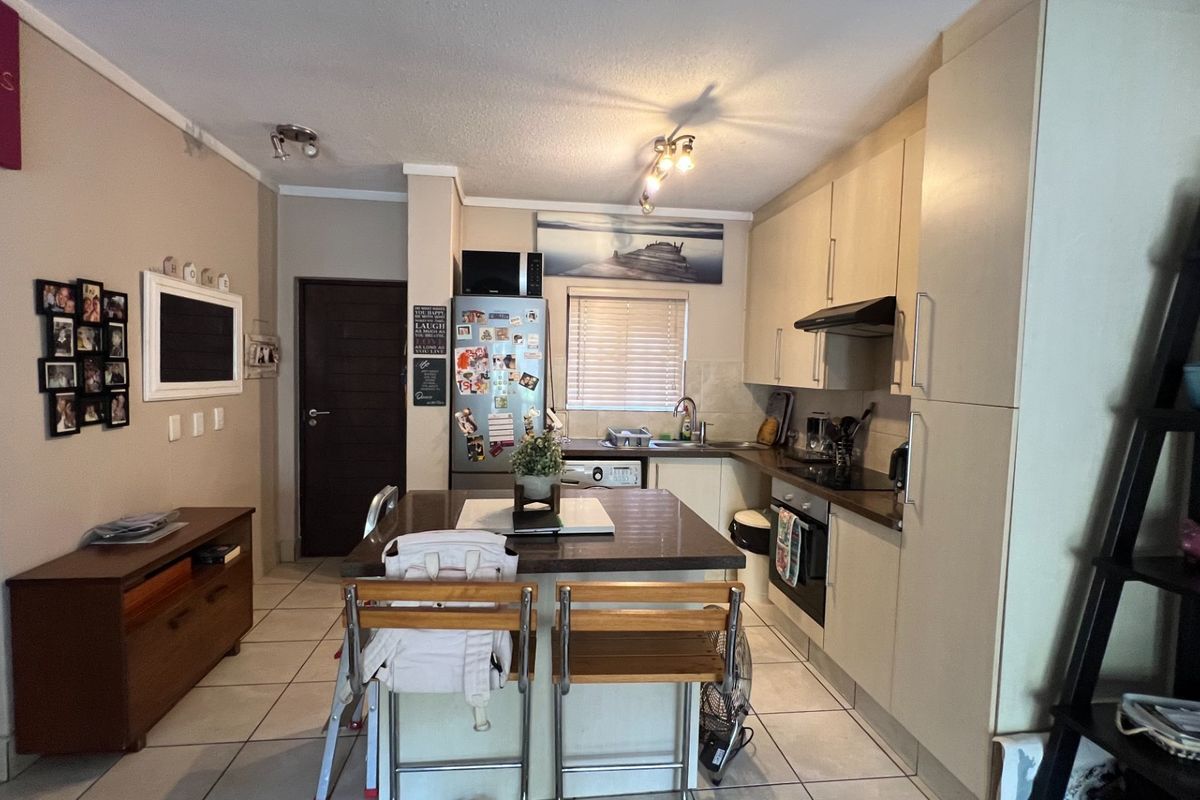 A functional kitchen featuring built-in cabinetry, a central island, integrated oven with extractor fan, and tiled flooring.