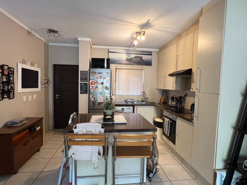 A functional kitchen featuring built-in cabinetry, a central island, integrated oven with extractor fan, and tiled flooring.