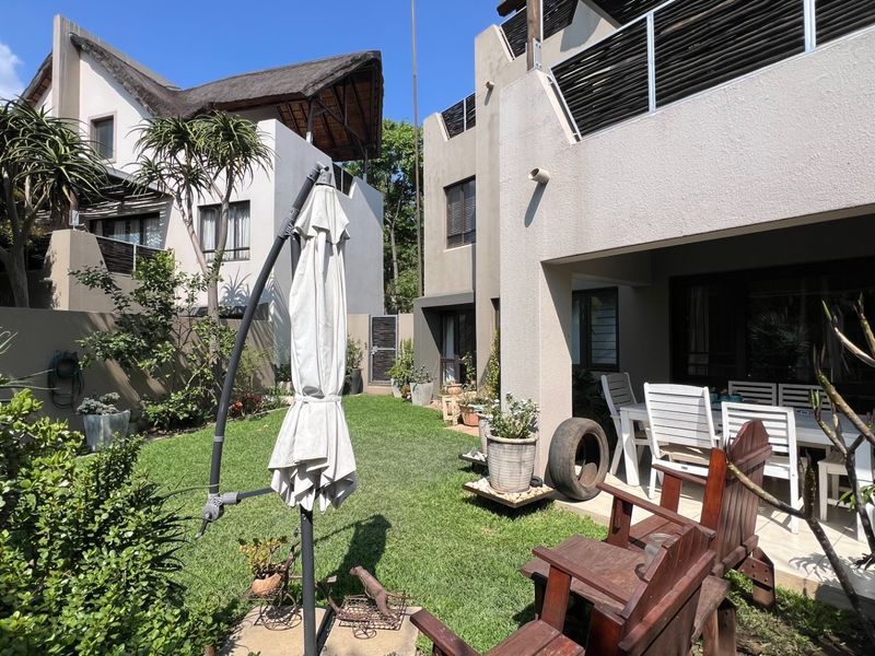 A private rear garden featuring a well-maintained lawn, a covered patio area, and a balcony overlooking the outdoor space.