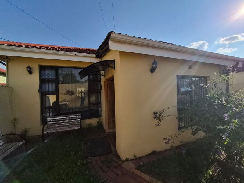 Front facade of a single-story house featuring tiled roofing, metal-framed windows with security bars, and a small entrance canopy.