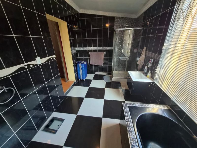A spacious bathroom featuring a black and white checkered tile design, a built-in bathtub, a separate shower enclosure, and a vanity basin.