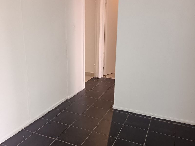 A vacant hallway featuring dark tiled flooring and an arched transition leading to adjacent rooms.