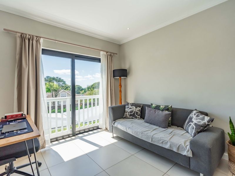 Bright living room featuring large sliding glass doors leading to a balcony, neutral tiled flooring, and recessed ceiling lighting.