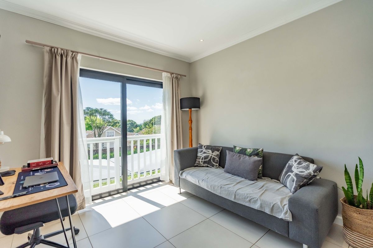 Bright living room featuring large sliding glass doors leading to a balcony, neutral tiled flooring, and recessed ceiling lighting.