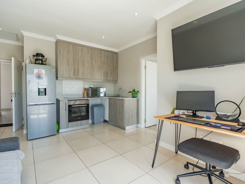 Open-plan living area featuring a modern kitchen with wood-finish cabinetry, built-in oven, and tiled flooring throughout.