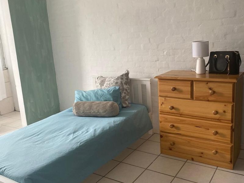 A simple bedroom featuring tiled flooring and a painted brick wall finish.