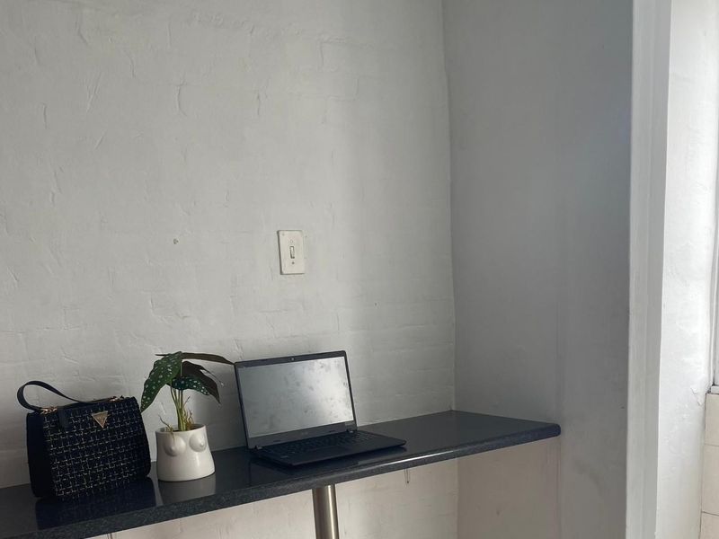 A compact office space featuring a built-in desk with a dark countertop and a wall-mounted electrical outlet.