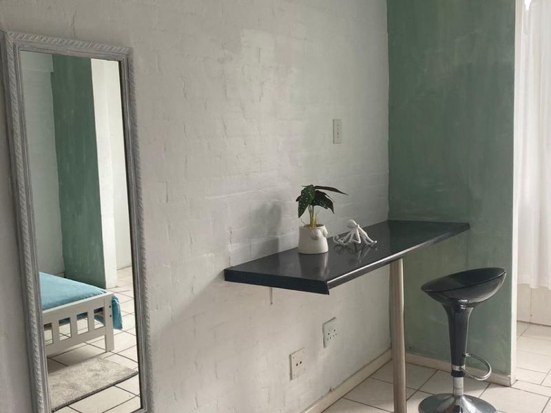 Bedroom featuring a wall-mounted desk, painted brick wall, and ceramic floor tiles.