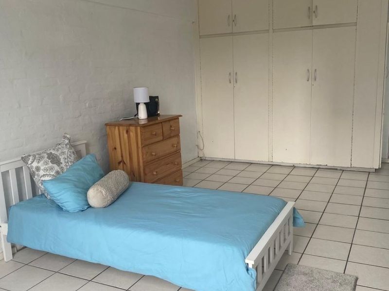 A bedroom featuring built-in cupboards and tiled flooring, offering a functional space with potential for cosmetic updates.