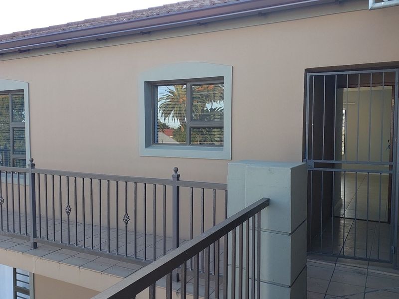 A covered balcony area featuring tiled flooring, a metal balustrade, and a secure entrance gate leading into the apartment.