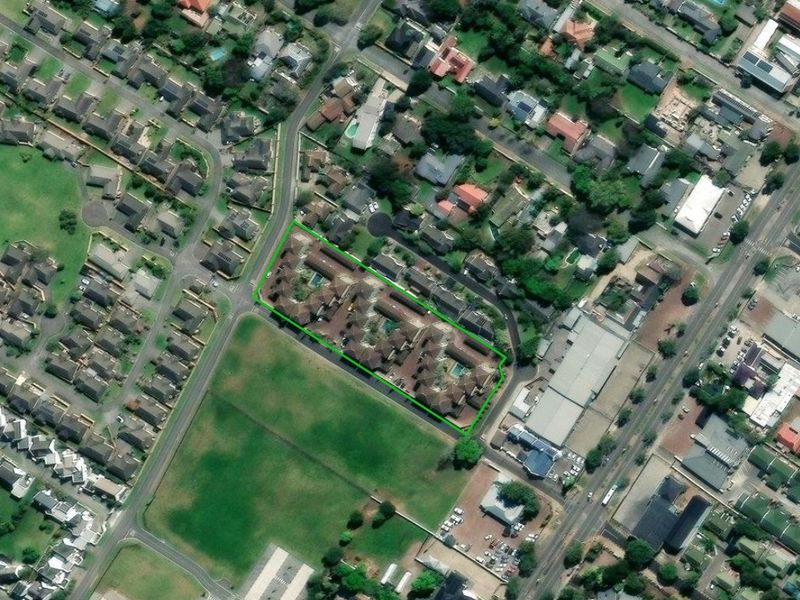 Aerial view of the apartment complex highlighting the property boundaries, roof layout, and communal swimming pool area within the residential neighborhood.
