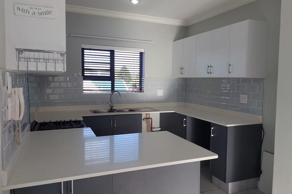 Modern kitchen featuring white upper cabinets, dark lower cabinetry, quartz countertops, subway tile backsplash, and a built-in gas hob.