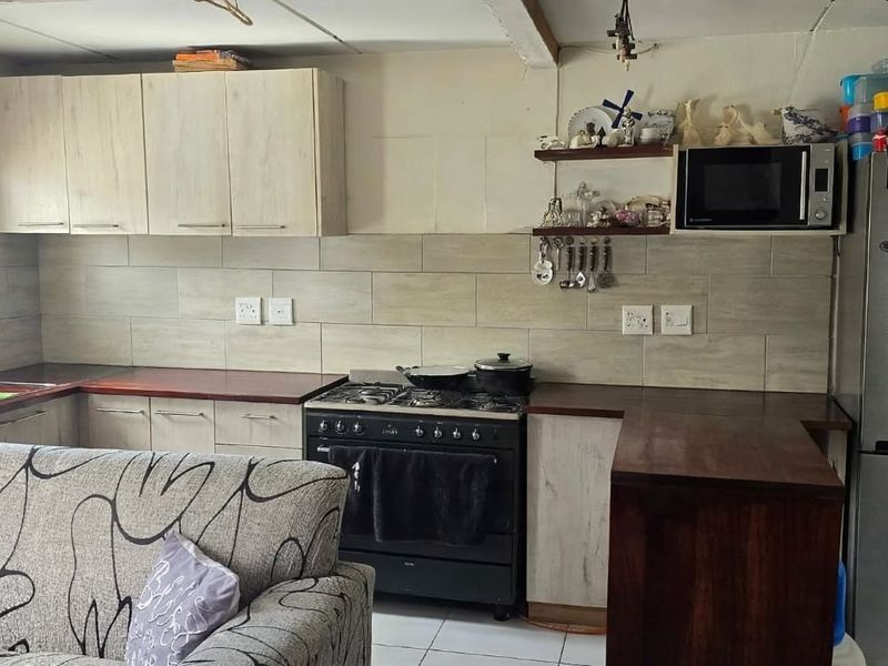 Open-plan kitchen featuring wooden countertops, gas stove, tiled backsplash, and ample built-in cabinetry, seamlessly integrated into the living space.