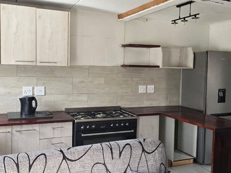 A functional kitchen featuring light wood-look cabinetry, a gas stove with oven, tiled backsplash, and a breakfast bar counter.