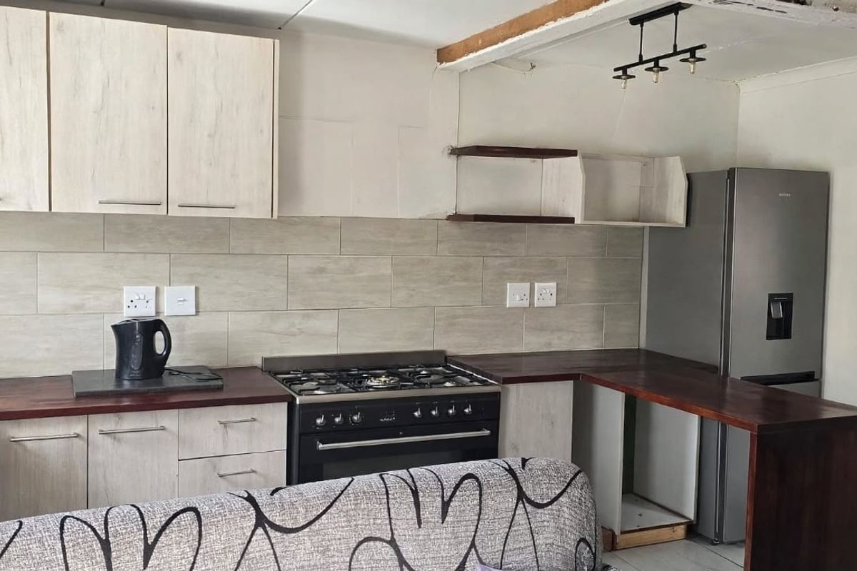 A functional kitchen featuring light wood-look cabinetry, a gas stove with oven, tiled backsplash, and a breakfast bar counter.
