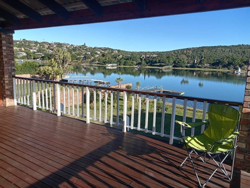 A spacious covered timber deck featuring a balustrade and exposed rafters, offering expansive views over the tranquil lake and surrounding landscape.