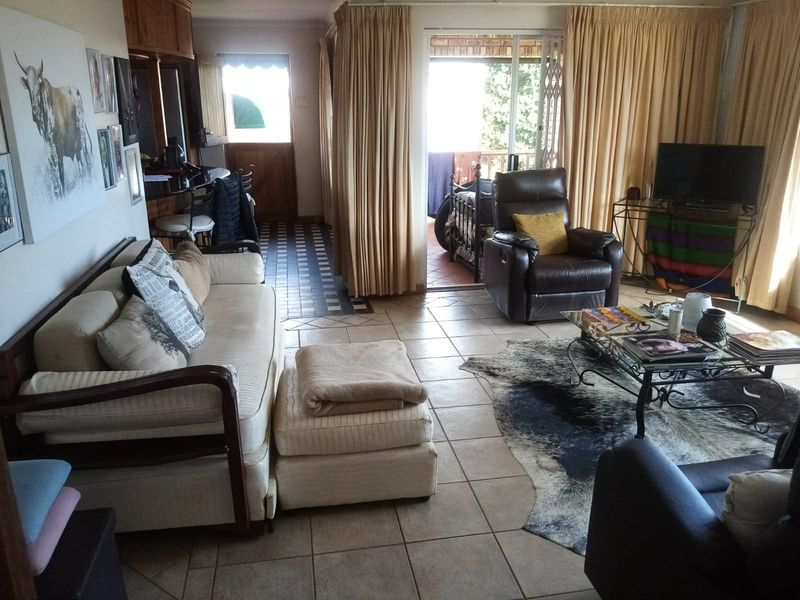 A living room featuring tiled flooring and a sliding glass door providing access to an outdoor patio area.
