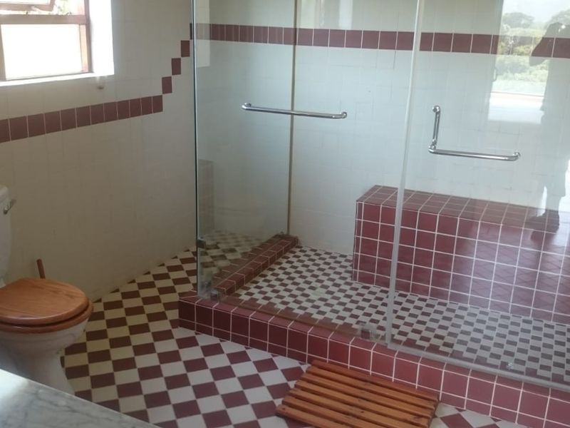 A functional bathroom featuring a walk-in shower with a built-in tiled bench, glass enclosure, and classic checkered tile flooring.