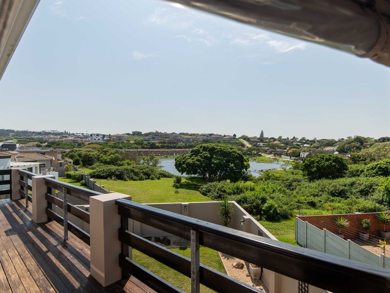 A spacious elevated timber balcony offering expansive views over the surrounding landscape, lake, and residential estate.