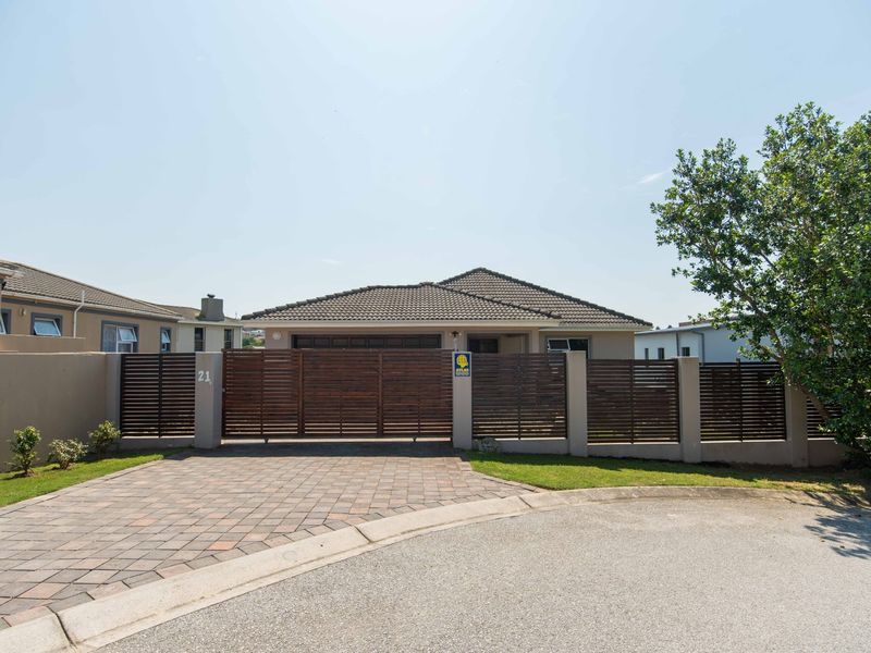 Front elevation of the property featuring a paved driveway, secure timber slat fencing, and a sliding gate entrance.