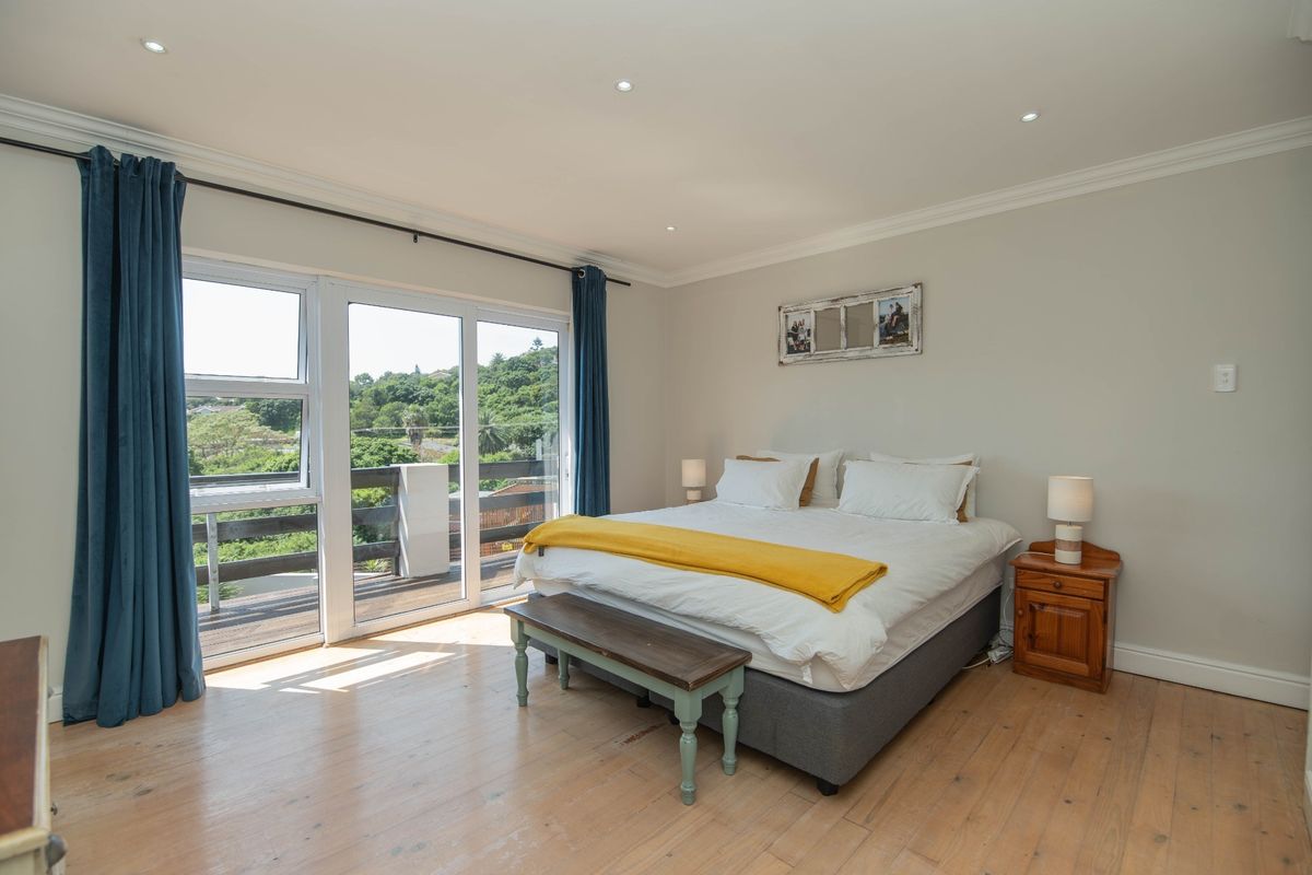 Spacious bedroom featuring timber flooring, crown molding, recessed lighting, and a large sliding glass door providing access to an outdoor balcony.