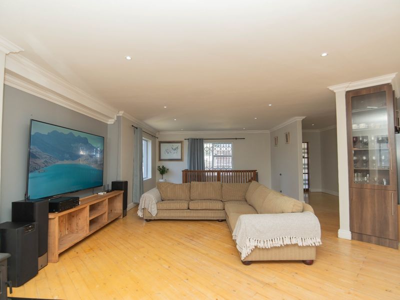 Spacious living room featuring timber flooring, recessed downlighting, crown molding, and a built-in display cabinet, offering a comfortable and well-maintained living space.