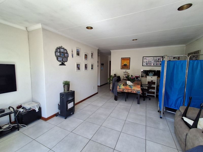 An open-plan living and dining area featuring neutral tiled flooring, recessed ceiling lighting, and coved cornicing throughout the space.