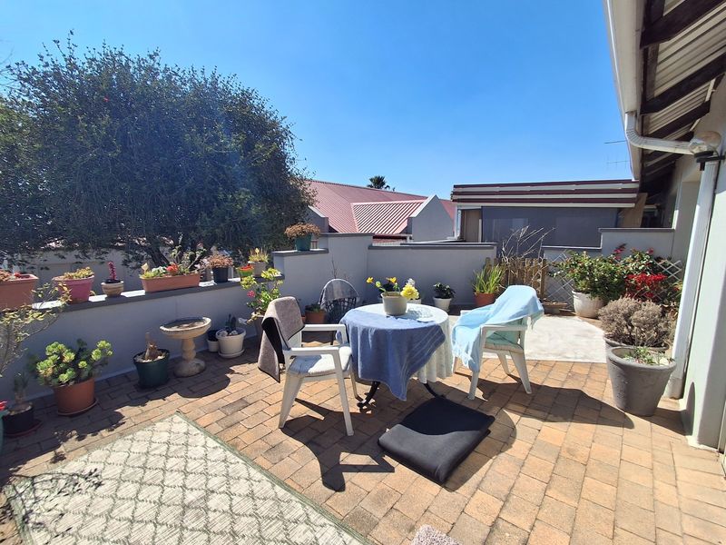 A sunny outdoor patio area featuring brick paving and a low parapet wall, providing a pleasant space for outdoor relaxation.