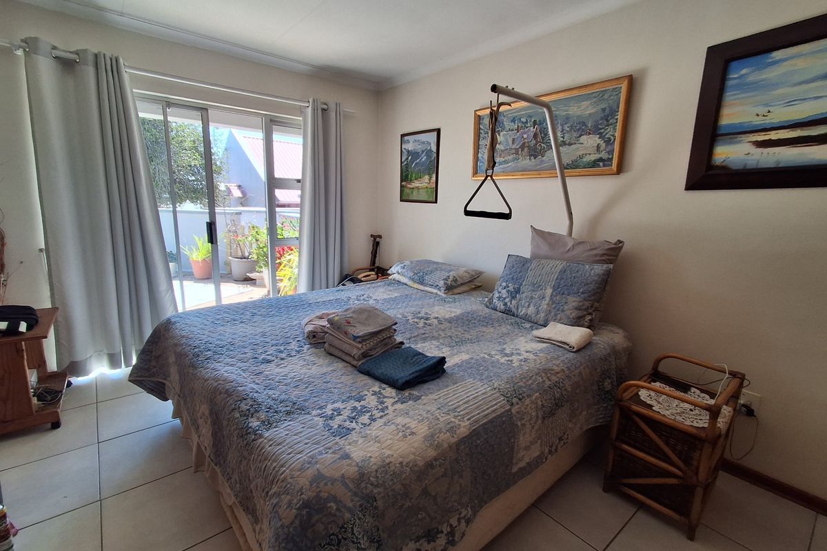 A bedroom featuring tiled flooring and a sliding glass door providing access to an outdoor patio area, equipped with a ceiling-mounted patient hoist.